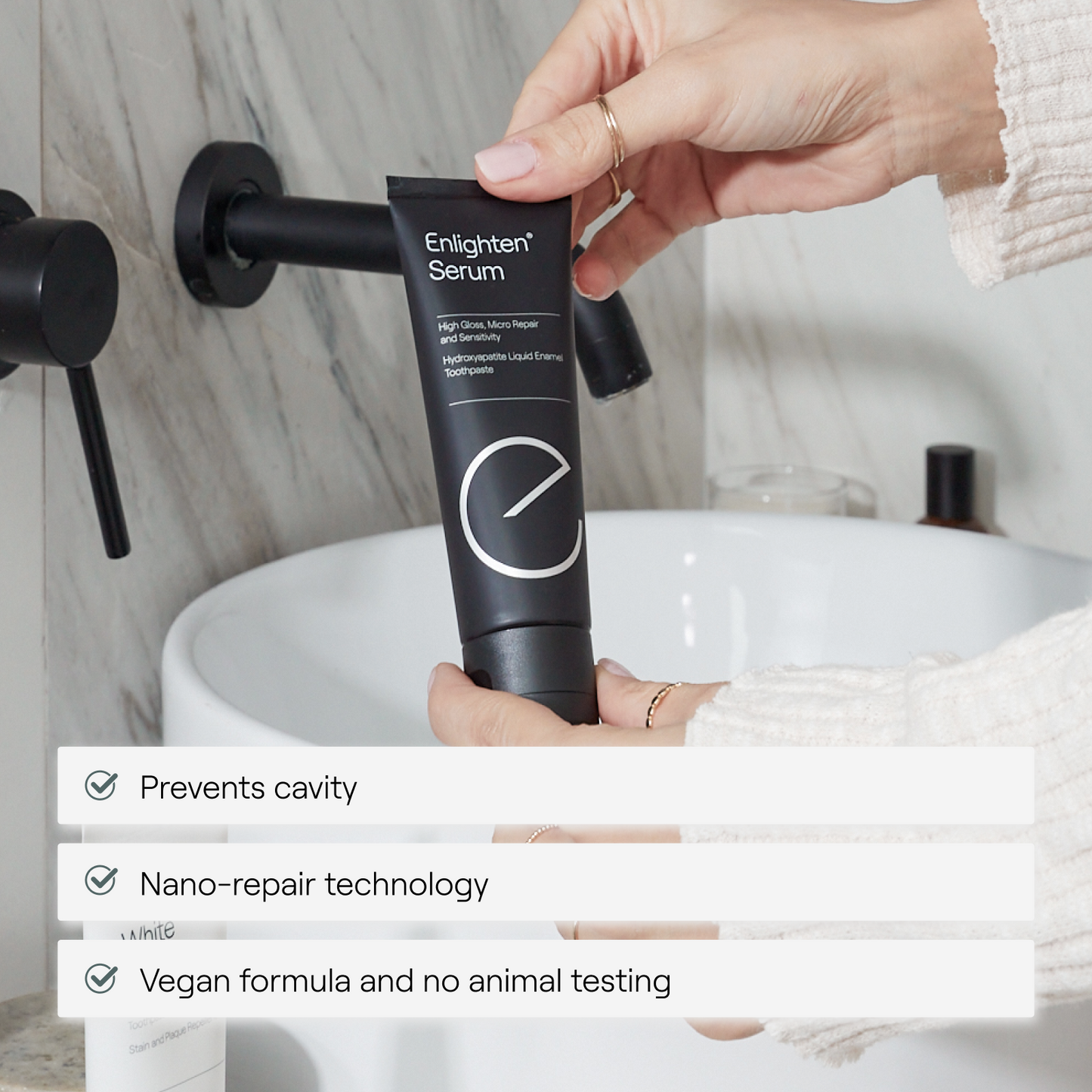 Woman’s hand holding Enlighten Serum with product benefits