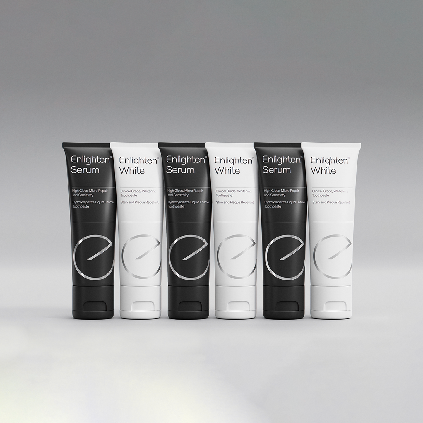 A lineup of Enlighten Serum and Enlighten White toothpaste tubes